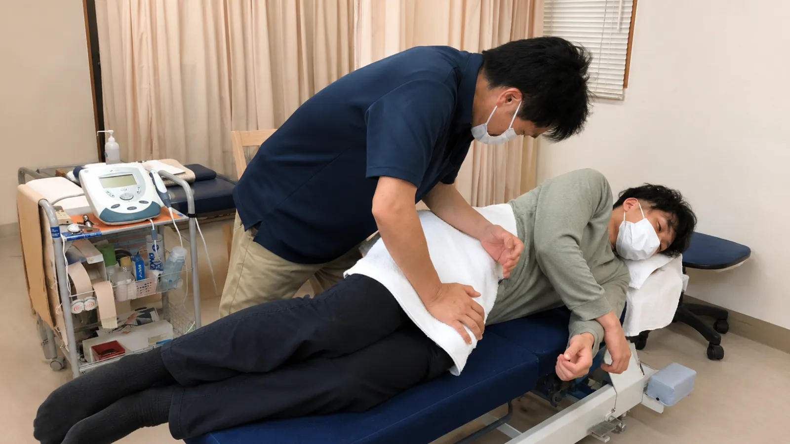 ぎっくり腰の患者さんの腰を確認し施術する石渡義敏院長